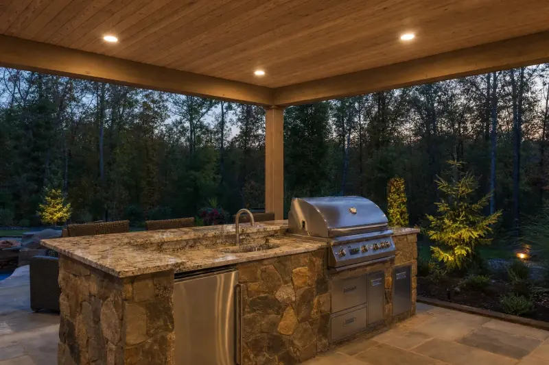 Stone grill island with a counter on a covered patio