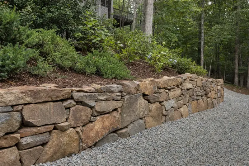 Stacked stone retaining wall holding a sloped garden bed